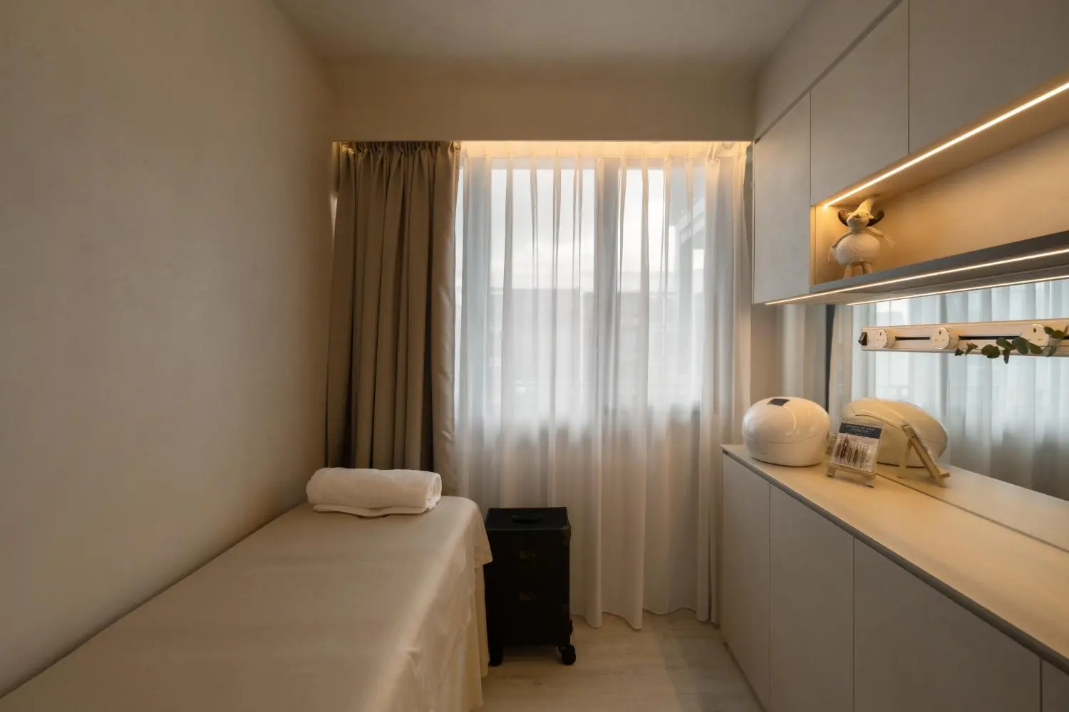 Facial treatment room — treatment table, sheer curtains and warm ambient light