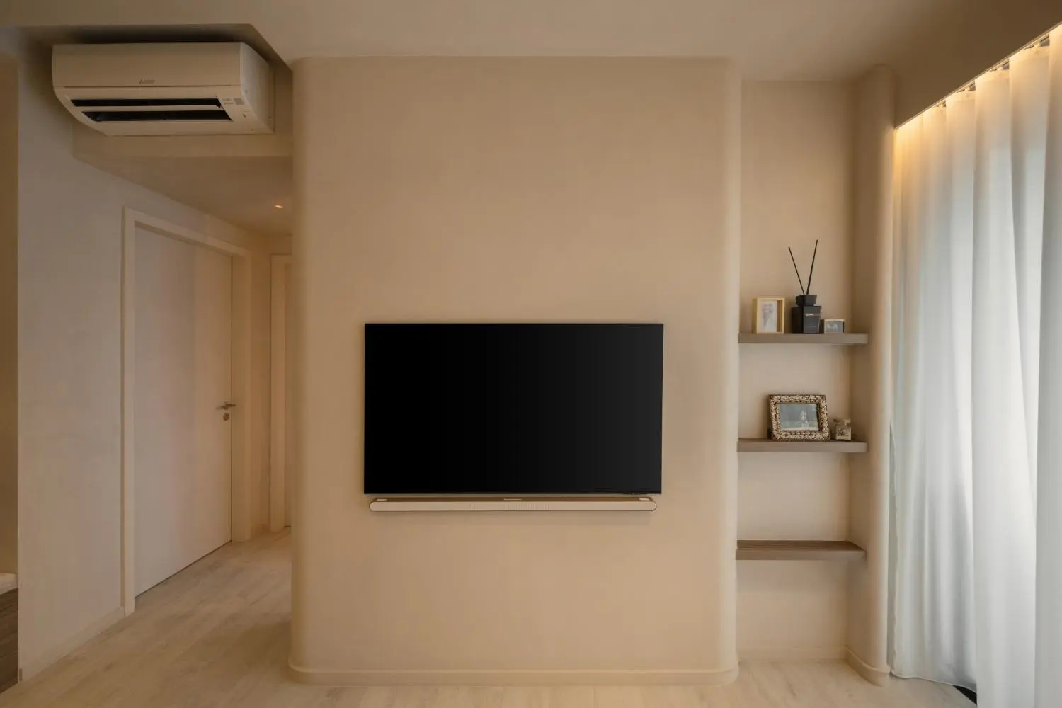 Bedroom TV wall — limewash surface, floating shelves and cove lighting